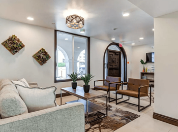 A living room with a grey couch, a coffee table, and a large arched doorway.